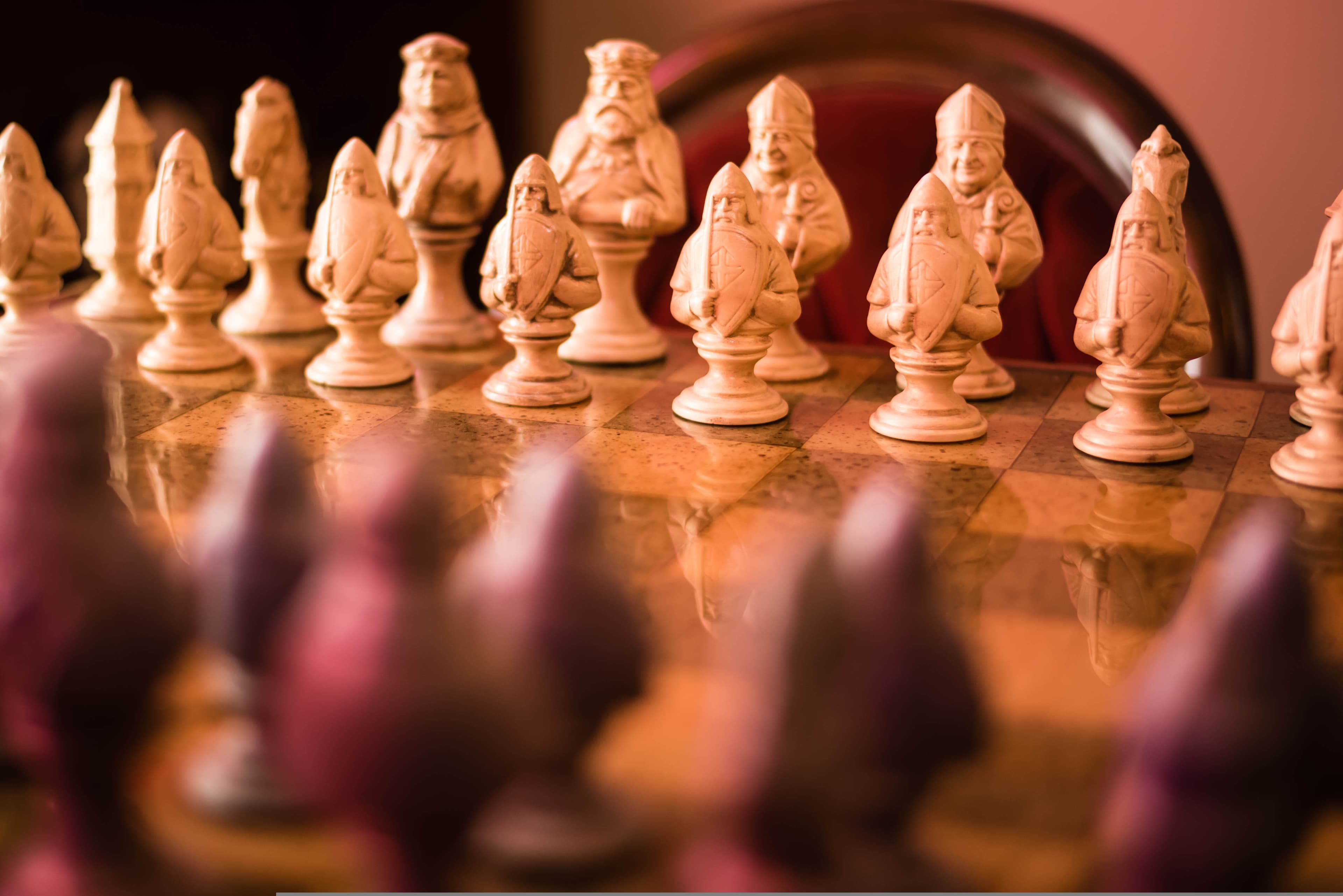 Ornate chess pieces lined up on a marble board, viewed from the opposing side — strategic positioning before the game begins